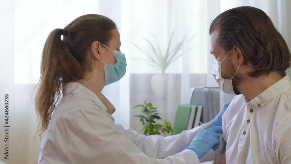Vaccination and prophylaxis against influenza or pandemic virus. a nurse in a mask and gloves makes an injection to a patient of a sick man in a clinic or hospital. Coronovirus - health concept. Vaccination and prophylaxis against influenza or pandemic virus. a nurse in a mask and gloves makes an injection to a patient of a sick man in a clinic or hospital. Coronovirus - health concept.