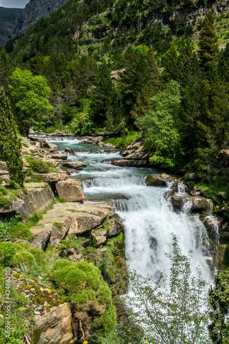 Sucesi  n de peque  as cascadas en un r  o de monta  a   rodeado por bosques y paredes de roca en el Parque Nacional de Ordesa  en los Pirineos espa  oles