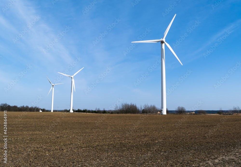 A group of windmills on a spring field. Alternative energy that does not pollute the environment. Caring for nature. A group of windmills on a spring field. Alternative energy that does not pollute the environment. Caring for nature.