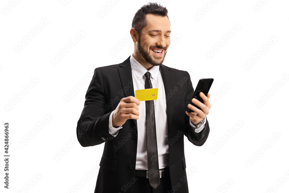 Smiling young professional man looking at a smartphone and holding a credit card Smiling young professional man looking at a smartphone and holding a credit card