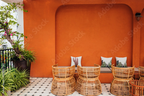 pillows against the background of an orange textured wall with a striped sofa in a modern cafe, stylish wooden chairs. Copy space