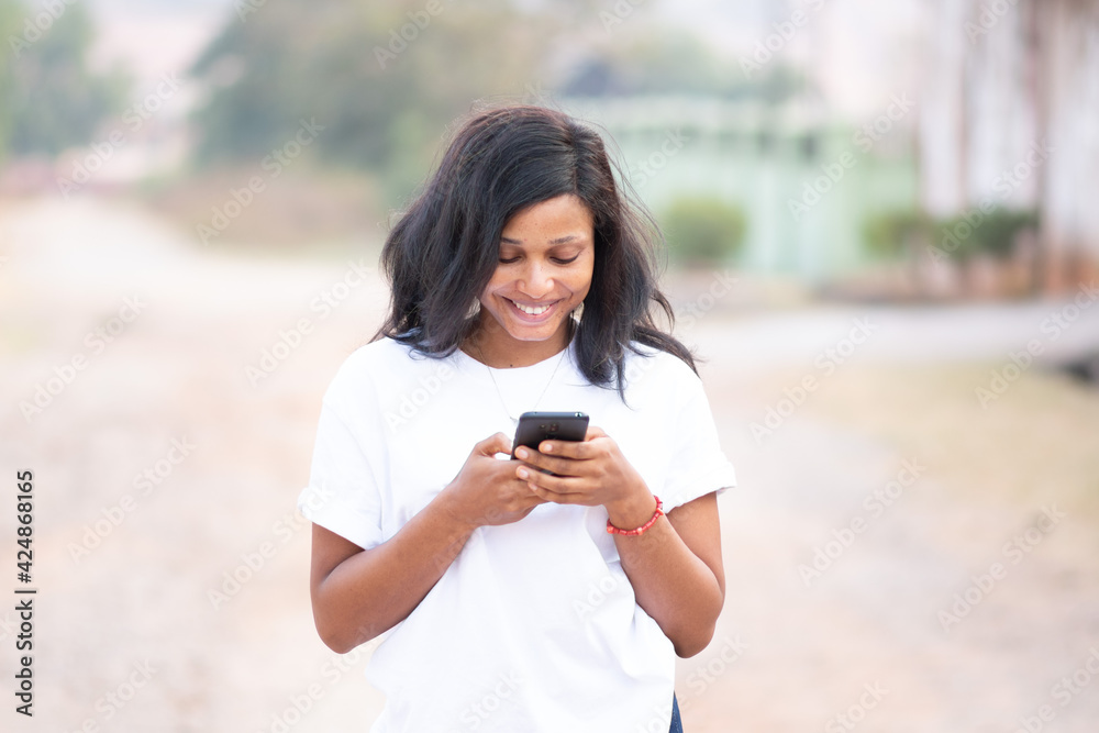 pretty young woman smiling while engaged with using her phone pretty young woman smiling while engaged with using her phone