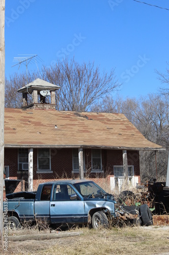 Old school house with broken down truck in front