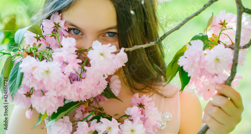 Spring girl. Beautiful teenager girl with brunette hair and smiling face in spring pink flower blossom sunny day closeup.