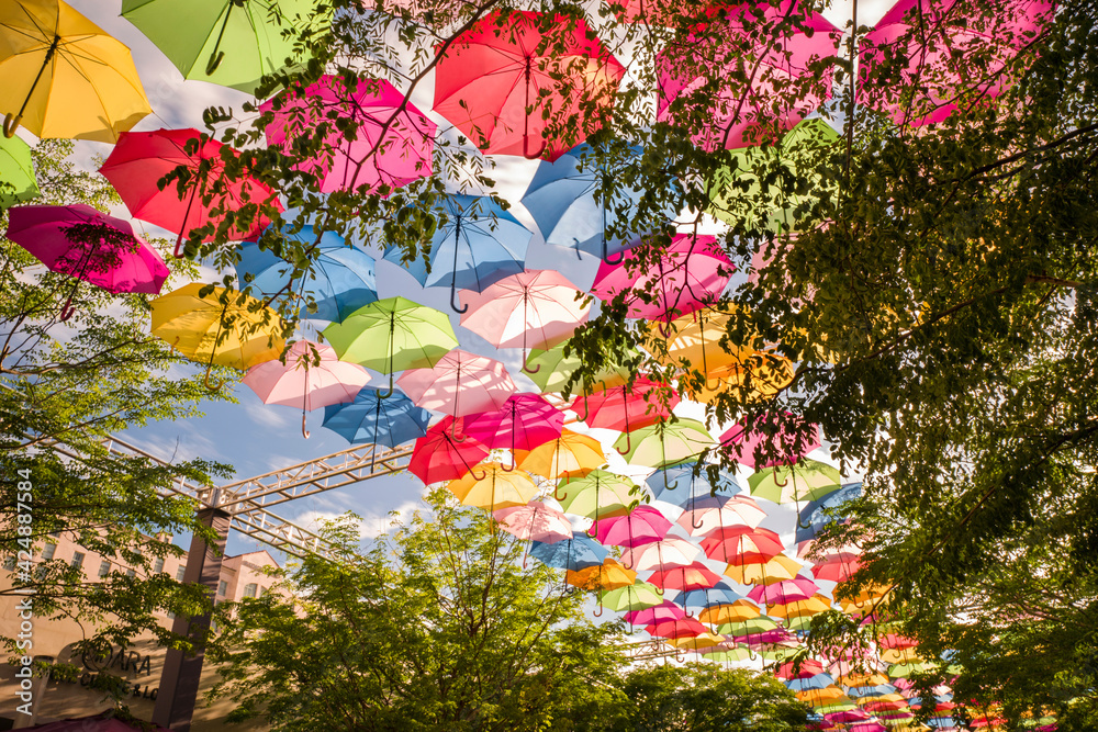 Colorful floating umbrellas hang above the street. Umbrella Sky Project