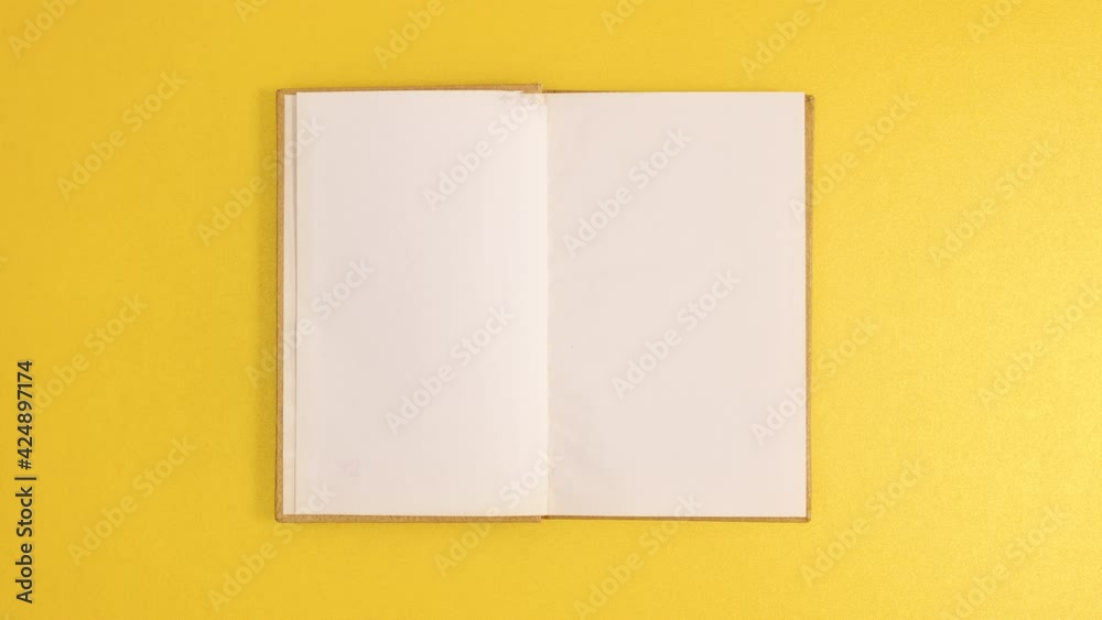 Golden vintage hardcover book appear and open with copy space on golden background. Stop motion flat lay