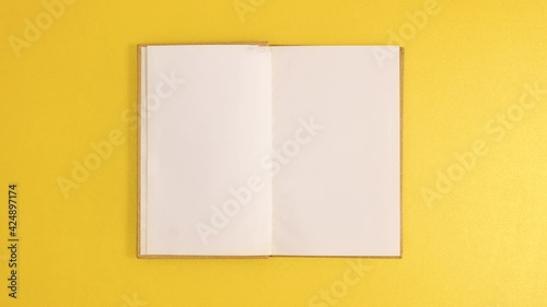 Golden vintage hardcover book appear and open with copy space on golden background. Stop motion flat lay
