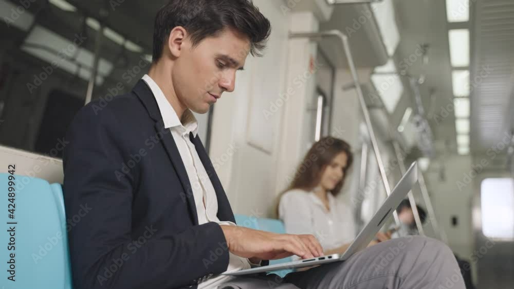 Businessman using laptop for working in the train and communicates on wireless headphones. Caucasian white male working on laptop while traveling by train. Businessman using laptop for working in the train and communicates on wireless headphones. Caucasian white male working on laptop while traveling by train.