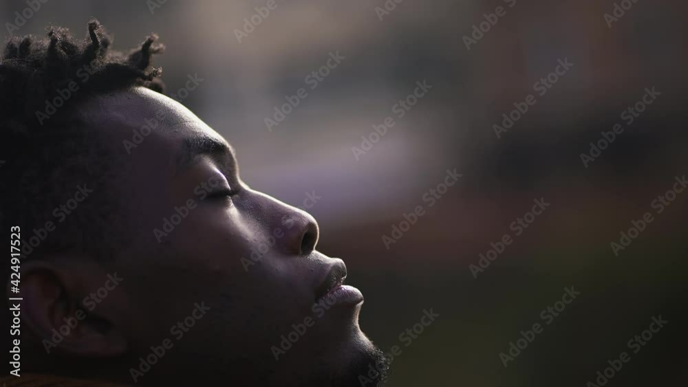 Meditative African man closing and opening eyes looking at sky smiling with FAITH and BELIEF