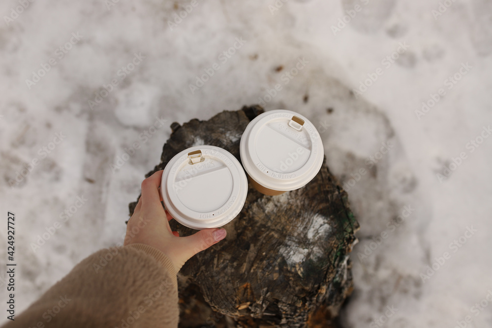 The girl takes hot coffee from the stump in the woods, a first-person view. The girl takes hot coffee from the stump in the woods, a first-person view.