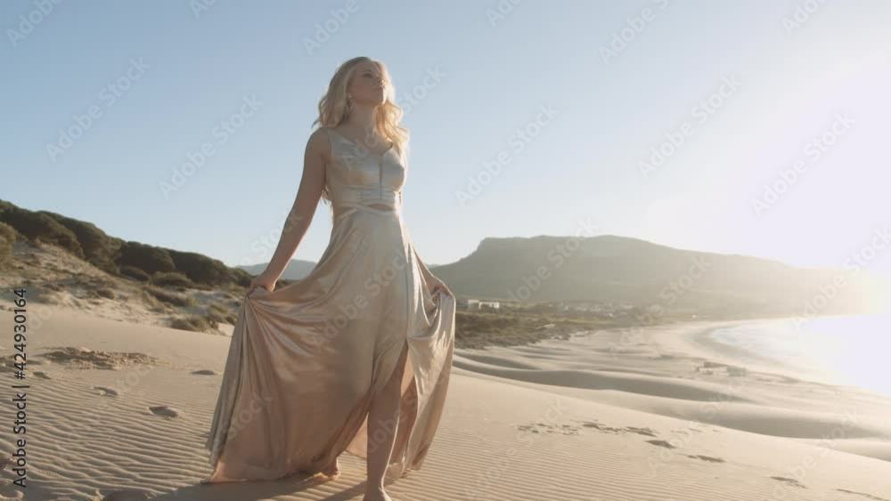 Beautiful Woman In Gold Walking Along Sandy Beach Beautiful Woman In Gold Walking Along Sandy Beach