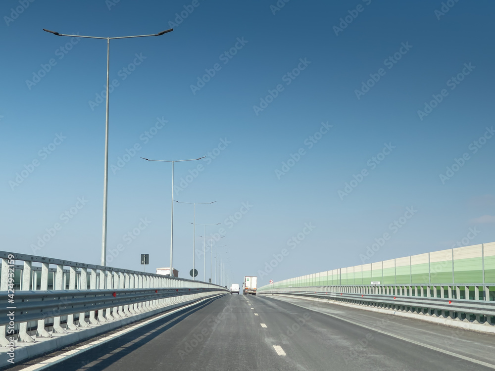 A7 highway in Romania connecting Moldova area with Bucharest. The part of the road next to Bacau city during a sunny day with blue sky. Indicator showing city names. A7 highway in Romania connecting Moldova area with Bucharest. The part of the road next to Bacau city during a sunny day with blue sky. Indicator showing city names.