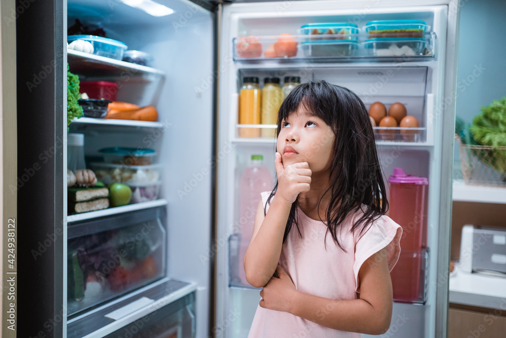 happy young asian girl open fridge door drinking a bottle of juice happy young asian girl open fridge door drinking a bottle of juice