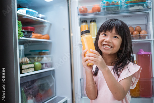 happy young asian girl open fridge door drinking a bottle of juice © Odua Images