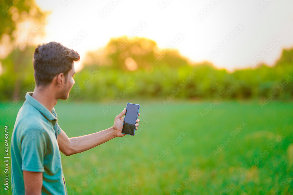 Young indian man showing smartphone screen at agriculture field. Young indian man showing smartphone screen at agriculture field.