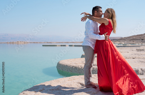 Romantic couple hug each other on the white beach of dead sea. Marriage in blue sea on paradise without borders. Love story woman and man in summer. vacation and travel in Israel