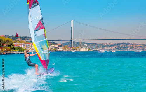 Windsurfer surfing the wind on waves - Ortakoy mosque and Bosphorus bridge - Istanbul, Turkey
