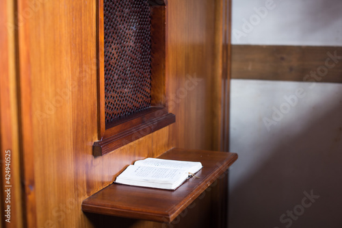 old priest inside the wooden confessional in a Christian church.