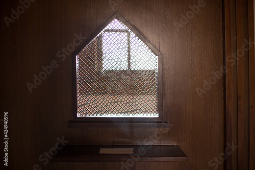 old priest inside the wooden confessional in a Christian church. photo