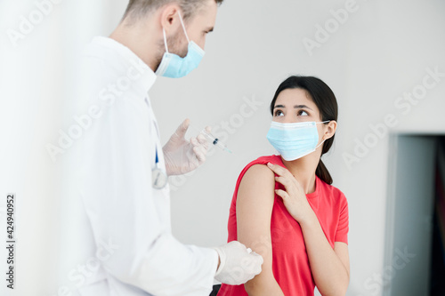 male doctor holding a syringe in his hands next to the patient injection covid 