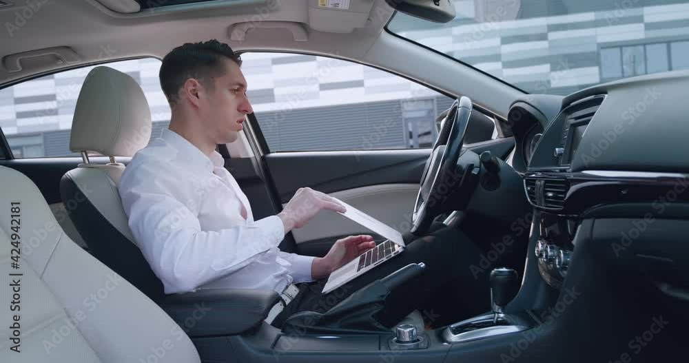 Frightened male businessman shocked by a bad message on a laptop, covers his mouth with his hand in fear, sitting in the car. Bankruptcy concept Frightened male businessman shocked by a bad message on a laptop, covers his mouth with his hand in fear, sitting in the car. Bankruptcy concept