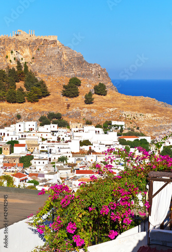 Greece. Rhodes island. Beautiful view on old town of Lindos with ancient Acropolis on top of mountain and traditional Greek white houses on historic part of town at summer sunset