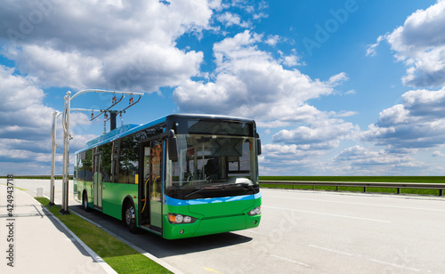 Electric bus at a stop is charged by pantograph 