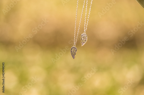 Set of best friends heart necklace shoot outside in a summer day closeup. Selective Focus. High quality photo