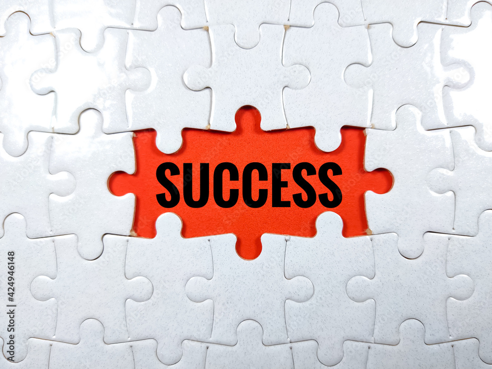 Selective focus.Word SUCCESS with magnifying glass and jigsaw puzzle on red background.Business concept.