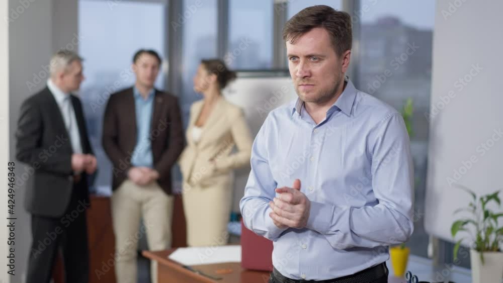 Nervous young Caucasian man screaming in office holding head in hands