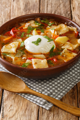 Pancutras Pantrucas is Chilean Soup with dumplings close up in the bowl on the table. Vertical photo