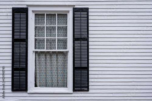 window with open shutters of an light colored wooden house