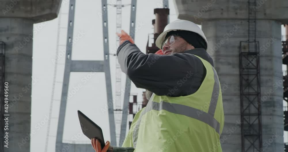 Male engineers discussing bridge drafts on tablet