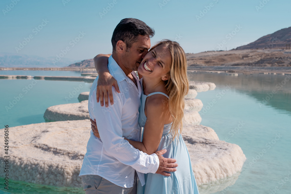 Romantic couple hug each other on the white beach of dead sea. Marriage in blue sea on paradise without borders. love story woman and man in summer. vacation and travel in Israel Romantic couple hug each other on the white beach of dead sea. Marriage in blue sea on paradise without borders. love story woman and man in summer. vacation and travel in Israel