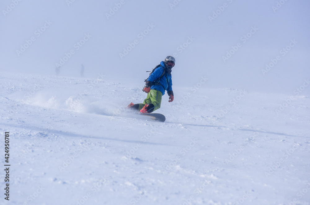 A guy in a red jumpsuit eating freeride on a snowboard on a snowy slope