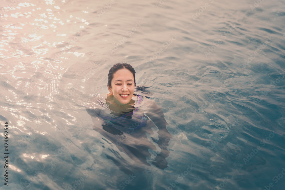 Beautiful woman smiling in a swimming pool under the summer light.