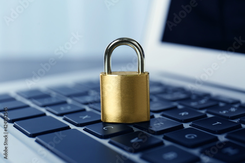 Metal padlock on laptop keyboard, closeup. Cyber security concept