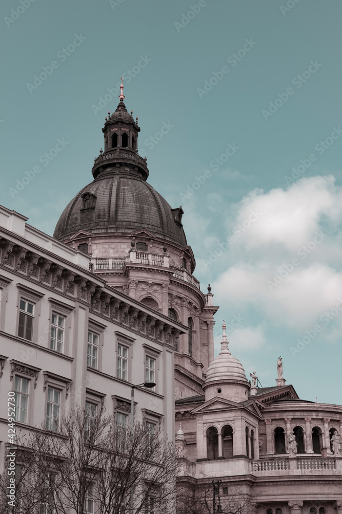 Apex of St. Stephen's Basilica in Budapest, Hungary and details of historical Hungarian downtown buildings on Street Bajcsy-Zsilinszky on a spring day, european architecture, aesthetics pastel colours