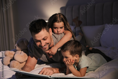 Father reading bedtime story to his children at home