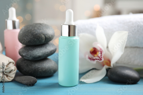 Beautiful spa composition with essential oil and orchid flower on turquoise table against blurred lights