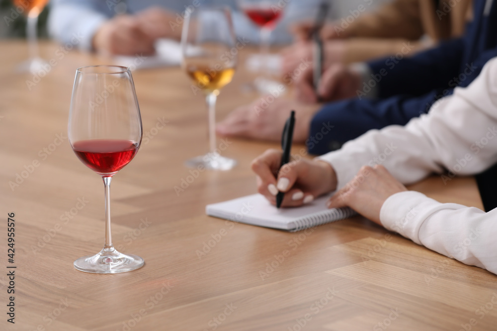Sommeliers making notes during wine tasting at table indoors, closeup Sommeliers making notes during wine tasting at table indoors, closeup