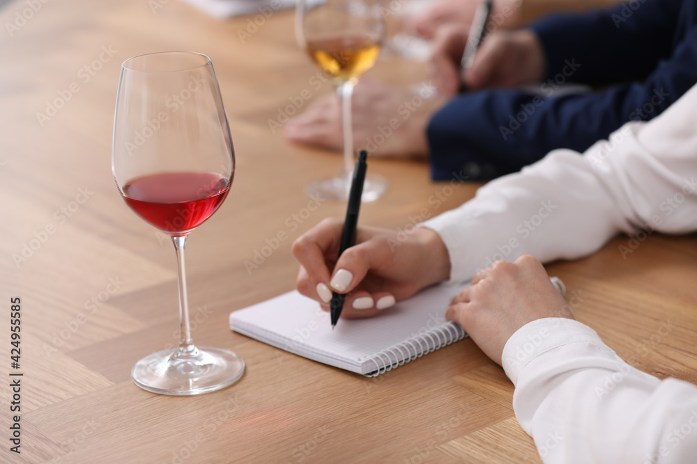 Sommeliers making notes during wine tasting at table indoors, closeup Sommeliers making notes during wine tasting at table indoors, closeup