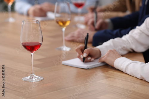 Sommeliers making notes during wine tasting at table indoors  closeup