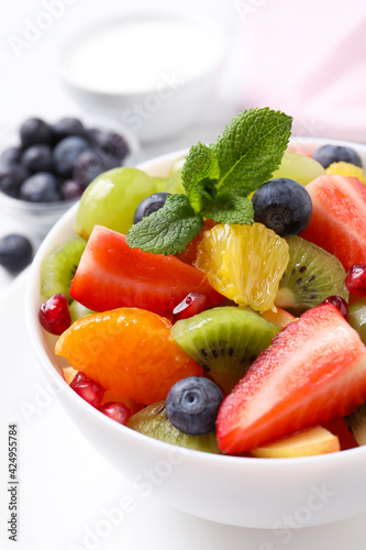 Delicious fresh fruit salad in bowl on table, closeup view