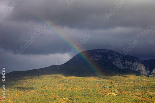 Beautiful Crimean landscape with a view of the mountains and a green valley and a rainbow in the clouds