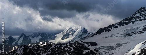 Nature background - dark stormy sky above snowy Russian Caucasus mountains in Elbrus region.