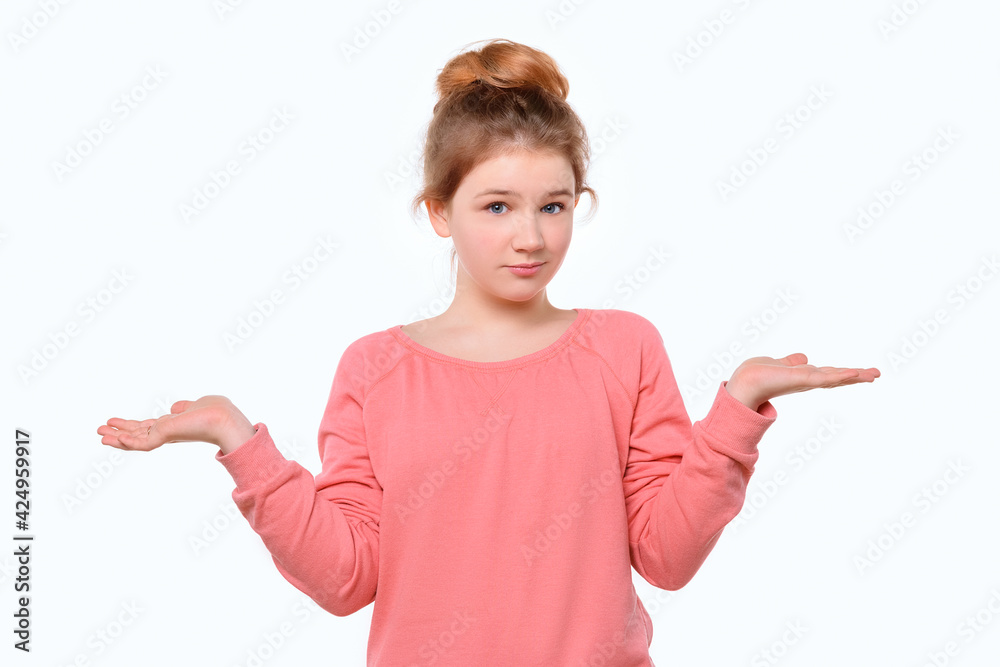 Confused young girl in pink casual sweatshirt shrugging shoulders. White background Confused young girl in pink casual sweatshirt shrugging shoulders. White background