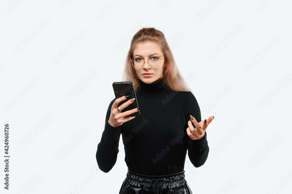 Image of a confused young beautiful woman in casual clothes holding her smart phone. White background Image of a confused young beautiful woman in casual clothes holding her smart phone. White background