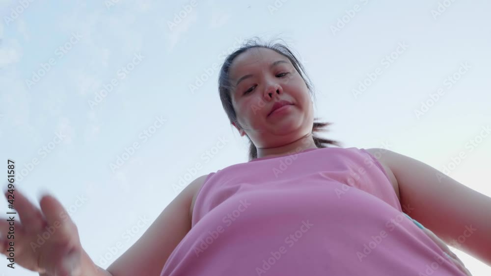 Unhappy boring overwieght of young sport Asian fat woman serious with belly stomatch. Slow motion plumply female try to lose weight by running in pink sportswear on sunset Unhappy boring overwieght of young sport Asian fat woman serious with belly stomatch. Slow motion plumply female try to lose weight by running in pink sportswear on sunset