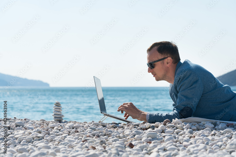 freelancer businessman working remotely on laptop at the beach near the zen pyramid